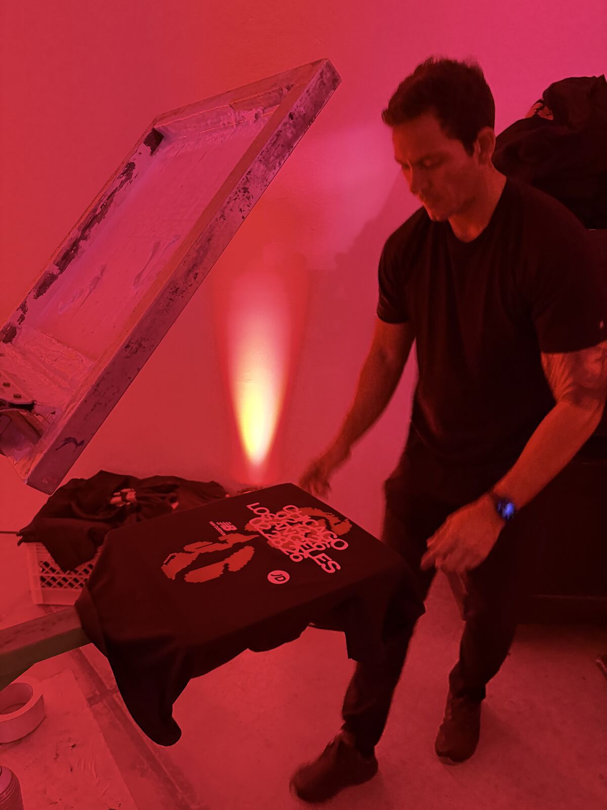 Heat press station with decorated totes and apparel displayed under dramatic red lighting