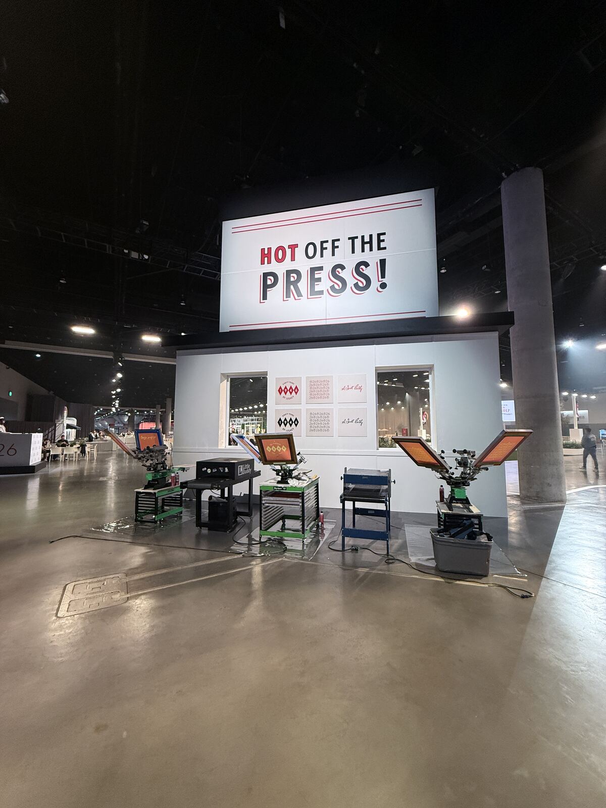 Indoor printing booth with a Hot Off the Press sign displaying screen printing and decoration equipment